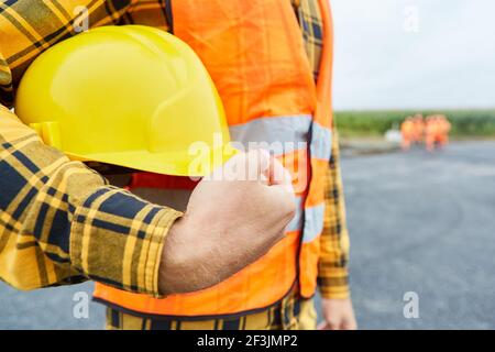 Travailleur sur le chantier de construction de routes avec casque de chantier pour la santé et la sécurité au travail Banque D'Images