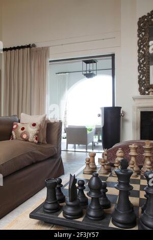 Échecs géants sur table basse dans le salon, avec vue sur la véranda | | Designer : Michael Nicholas Banque D'Images