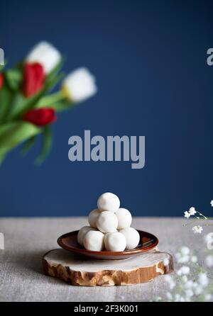 Kazakh et kirghize nourriture nationale kurt ou kurut balles blanches salées de fromage sec près des fleurs pendant le festival Nauryz sur fond bleu foncé. Spac libre Banque D'Images