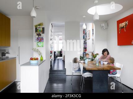 Vue de la cuisine/salle à manger à l'étude en passant par le salon avec repas en famille. | architecte : Justin Nicholls | Concepteur : Justin Nicholls Banque D'Images