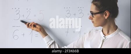 leçon de mathématiques - enseignant montrant des équations mathématiques simples sur tableau blanc en classe Banque D'Images