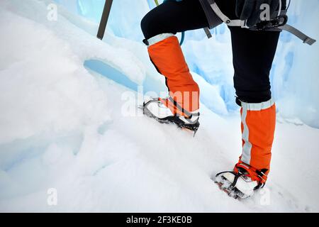 Femme grimpant dans des guêtres orange avec hache glacée près de la cascade gelée dans les montagnes à Almaty, Kazakhstan Banque D'Images