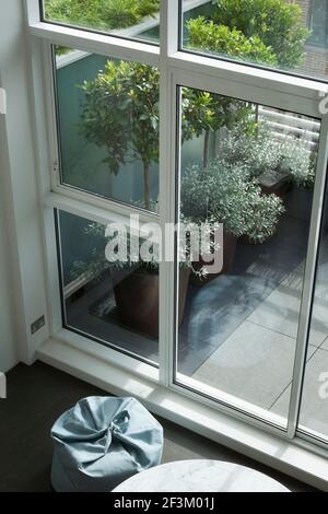 BEAB sac/pouffe à l'intérieur de la salle de séjour principale au niveau de la terrasse, avec façade en verre et fenêtres à la terrasse. Jardinières de cuivre plantées de coupe Banque D'Images