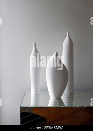 Trois vases en porcelaine blanche sur un côté miroir dans un appartement français. Banque D'Images