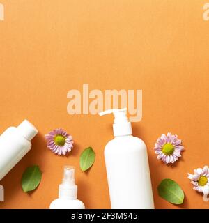 Salle de bains avec bouteilles blanches sur fond orange. plan d'eau, vue sur le dessus, espace copie. Soins de la peau et concept spa Banque D'Images