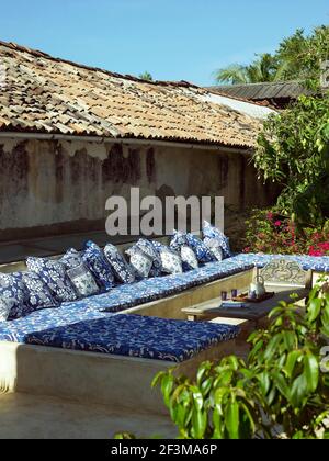 Coin salon extérieur avec une couverture et des coussins aux couleurs vives à côté d'un toit carrelé dans le jardin de la maison résidentielle au Sri Lanka. Banque D'Images