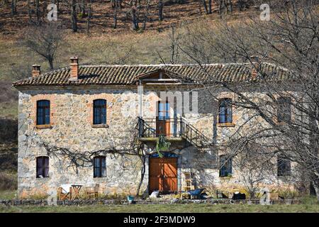 Paysage rural avec vue sur une maison traditionnelle en pierre abandonnée à Oxia, un village pastoral de l'Ouest de la Macédoine dans le lac Prespa, Grèce. Banque D'Images