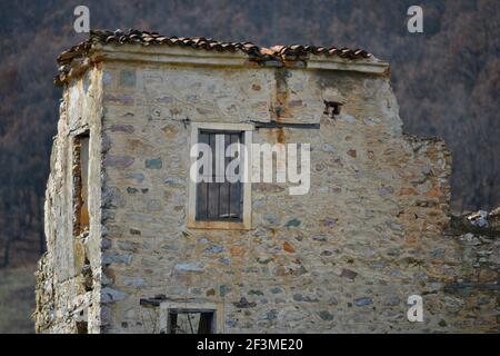 Paysage rural avec vue sur une maison traditionnelle en pierre abandonnée à Oxia, un village pastoral de l'Ouest de la Macédoine dans le lac Prespa, Grèce. Banque D'Images