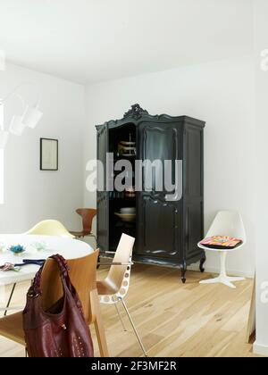 Table ronde, chaises et armoire noire dans une pièce blanche avec parquet dans une maison résidentielle, Danemark Banque D'Images