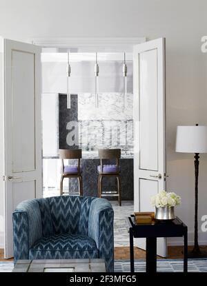 Fauteuil bleu devant une porte ouverte avec vue sur la cuisine dans l'appartement de Bangkok, Thaïlande Banque D'Images