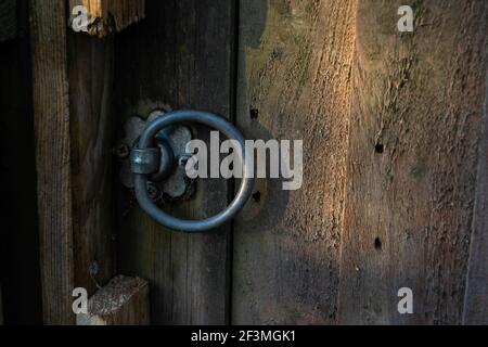 Gros plan sur la porte de jardin avec bouton métallique rond, porte en bois avec poignée en forme circulaire, ancienne clôture en bois avec porte verrouillée Banque D'Images