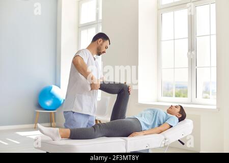 Jeune homme ostéopathe contrôlant les articulations de la femme couchée patients jambes Banque D'Images