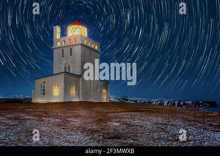 Phare de Dyrholaey sous les sentiers étoiles. La station de lumière de Dyrholaey a été établie en 1910, près du village de Vik, à l'extrémité sud de l'Islande. Banque D'Images