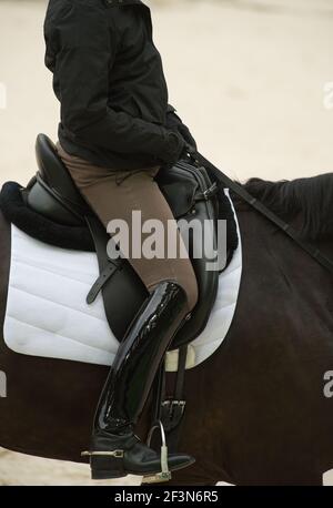 Cavalier de dressage équestre dans le siège de dressage approprié montrant le grand noir bottes de dressage beige jodhpurs anglais cuir dressage selle blanc selle bloc Banque D'Images