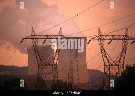 Centrale nucléaire de Tricastin. Près de Montélimar. Vapeur provenant de cheminées de grande taille. Ciel orange. Pylônes. Banque D'Images