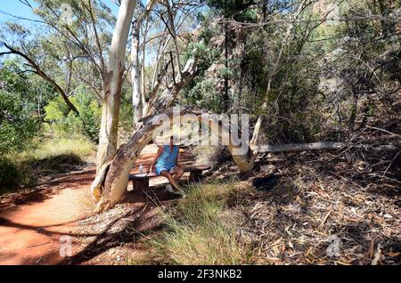 Australie, dans le territoire du Nord, une femme se repose sur le chemin de Standley Chasm dans le parc national de West McDonnell Range Banque D'Images