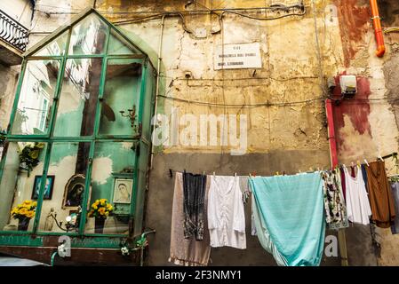 Naples, Italie - 9 septembre 2019 : autel avec offrandes et vêtements suspendus dans une rue du centre historique de Naples, Italie Banque D'Images