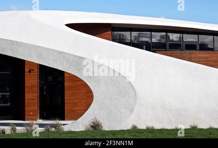 Une structure externe courbée blanche et spectaculaire autour d'un bâtiment qui offre des espaces de traitement et sociaux pour les patients atteints de cancer, dans le domaine d'un hôpital. Banque D'Images