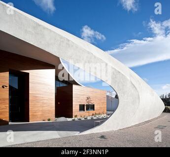 Une structure externe courbée blanche et spectaculaire autour d'un bâtiment qui offre des espaces de traitement et sociaux pour les patients atteints de cancer, dans le domaine d'un hôpital. Banque D'Images