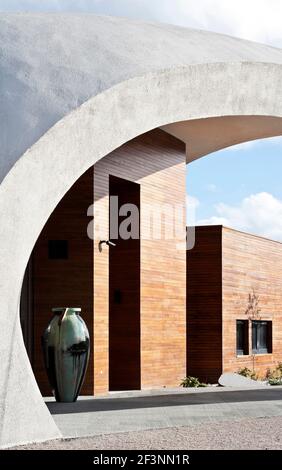 Une structure externe courbée blanche et spectaculaire autour d'un bâtiment qui offre des espaces de traitement et sociaux pour les patients atteints de cancer, dans le domaine d'un hôpital. Banque D'Images