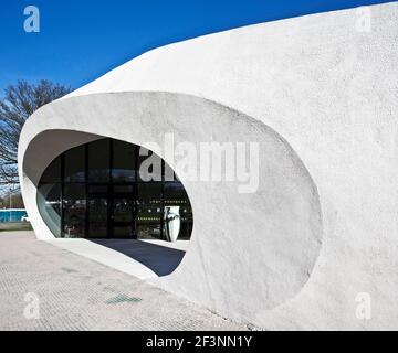 Une structure externe courbée blanche et spectaculaire autour d'un bâtiment qui offre des espaces de traitement et sociaux pour les patients atteints de cancer, dans le domaine d'un hôpital. Banque D'Images