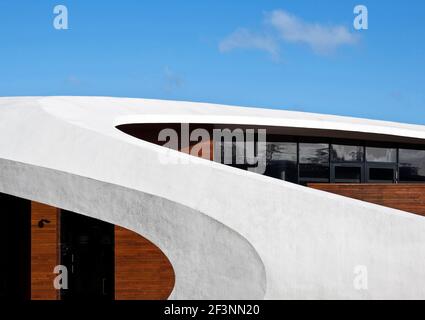 Une structure externe courbée blanche et spectaculaire autour d'un bâtiment qui offre des espaces de traitement et sociaux pour les patients atteints de cancer, dans le domaine d'un hôpital. Banque D'Images