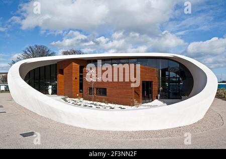 Une structure externe courbée blanche et spectaculaire autour d'un bâtiment qui offre des espaces de traitement et sociaux pour les patients atteints de cancer, dans le domaine d'un hôpital. Banque D'Images