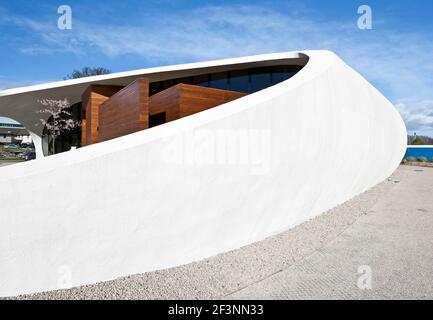 Une structure externe courbée blanche et spectaculaire autour d'un bâtiment qui offre des espaces de traitement et sociaux pour les patients atteints de cancer, dans le domaine d'un hôpital. Banque D'Images