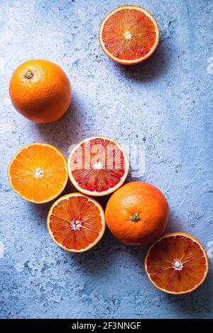 Oranges de sang juteuses entières et mûres tranchantées sur table bleue. Banque D'Images