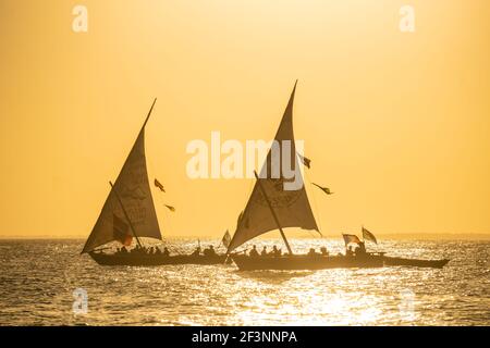 Coucher de soleil avec deux dhows dans une distance. Les dhuws sont des bateaux à voile en bois, principalement utilisés dans l'océan indien, pour transporter des marchandises d'un endroit à un autre Banque D'Images