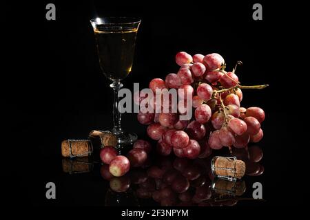 Grappes de raisins roses et de pommes vertes sur fond sombre. Un verre de champagne est en arrière-plan. Encore la vie. Panier de vitamines. Copier l'espace. Banque D'Images