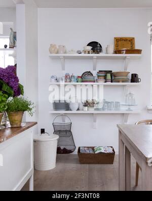 Claire, chaleureuse et chaleureuse, Scandinavie. Un coin de la cuisine, des piles d'objets sur un ensemble d'étagères, des murs peints en blanc et du bois de style scandinave Banque D'Images