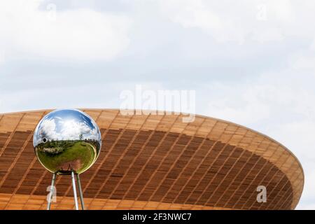 Une sphère réfléchissante sculpture avec le vélodrome en arrière-plan, le Parc Olympique, Stratford, London, E15. Banque D'Images