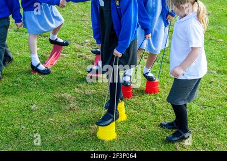 Les enfants de l'école primaire jouant sur des pilotis à l'extérieur dans une aire de jeux de l'école pendant une pause des leçons. Banque D'Images