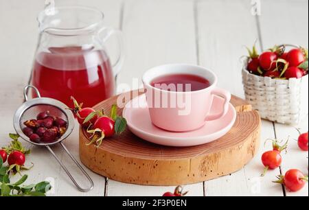 Tasse de thé aux hanches roses et hanches roses fraîches à côté il Banque D'Images