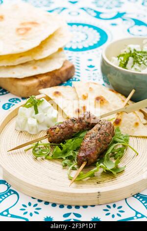 Kofta d'agneau aux feuilles de roquette servies avec une salade de pommes de terre halées et du pain plat Banque D'Images