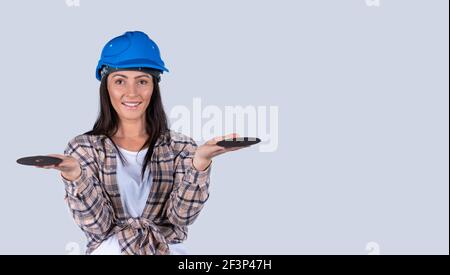 Bannière,format long.Une femme de main dans un casque bleu regarde la caméra avec un sourire et tient des disques abrasifs avec les deux mains.Arrière-plan blanc Banque D'Images