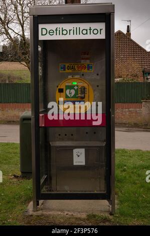 Un défibrillateur cardiaque d'urgence dans un ancien coffret téléphonique dans un village anglais rural Banque D'Images