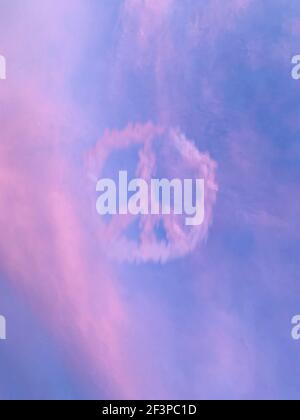 Symbole de paix flou fait de nuages sur rose et bleu ciel Banque D'Images