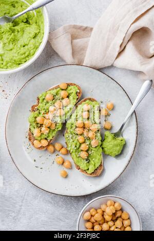 Toasts vegan à l'avocat avec pois chiches et graines de chanvre sur une assiette, vue du dessus. Dieting, concept de manger propre. Fond en béton gris Banque D'Images