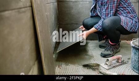 Femme de construction posant un nouveau plancher de carreaux Banque D'Images