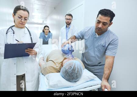 Équipe de médecins qui sauvent le patient sur le lit qu'il exécute une réanimation avec défibrillateur en cas d'urgence Banque D'Images