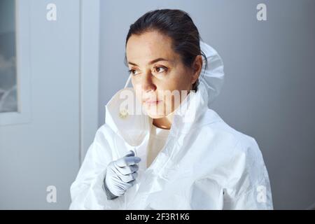Jeune femme médecin en vêtement de protection debout dans le couloir de l'hôpital après utilisation Banque D'Images
