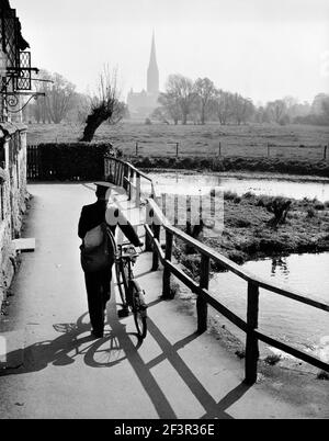 HARNHAM, Salisbury, Wiltshire. Vue depuis le vieux moulin de Harnham, en regardant de l'autre côté des prés d'eau vers la cathédrale de Salisbury avec un postier poussant Banque D'Images