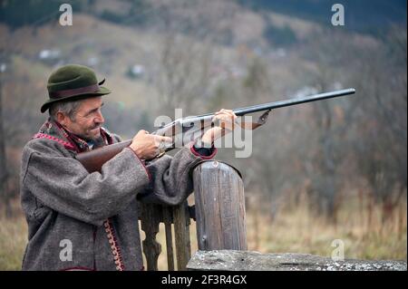 Un chasseur avec une arme dans ses mains pour la chasse les vêtements prennent le but et sont prêts à filmer Banque D'Images