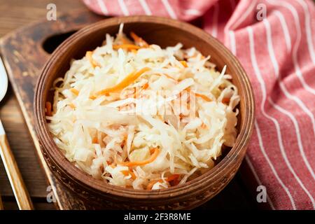 Choucroute, chou fermenté avec carottes dans un bol sur fond de bois, gros plan. Superaliments pour soutenir le système immunitaire. Banque D'Images
