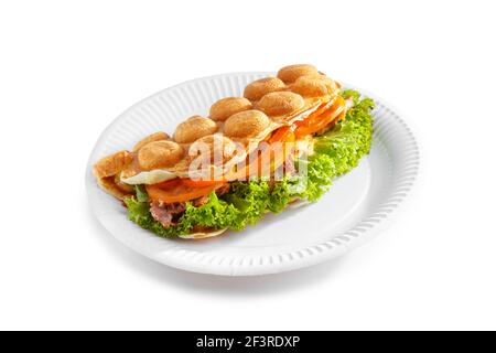 Gaufres à bulles à Hong Kong. Gaufre à bulles avec bacon frit, œufs, tomate et salade sur l'assiette en papier isolée sur fond blanc. Banque D'Images