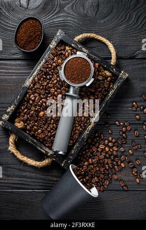 Café moulu en Portafilter pour expresso dans un plateau en bois avec grains de café. Arrière-plan en bois noir. Vue de dessus Banque D'Images