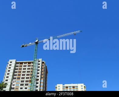 Vue de dessous de deux nouveaux bâtiments à plusieurs étages et d'une construction grue sur fond bleu ciel Banque D'Images