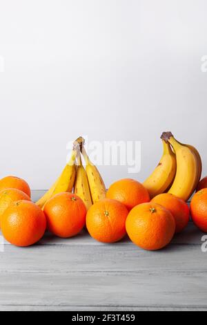 Vue sur les oranges et les bananes alignées sur un gris tableau sur fond blanc Banque D'Images